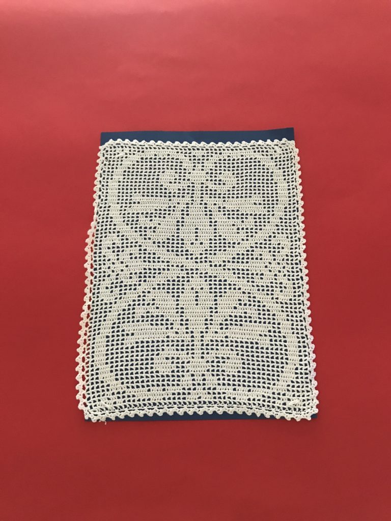 Motivo Decorativo: La lavorazione forma un disegno centrale simmetrico, probabilmente floreale o ornamentale, racchiuso da una cornice perimetrale geometrica.